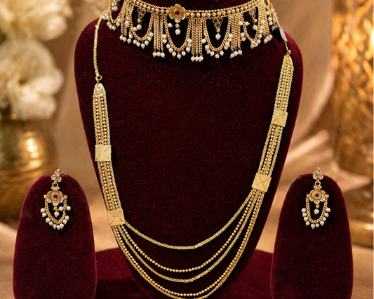 Gold necklace and earrings set on a red velvet stand with a soft background