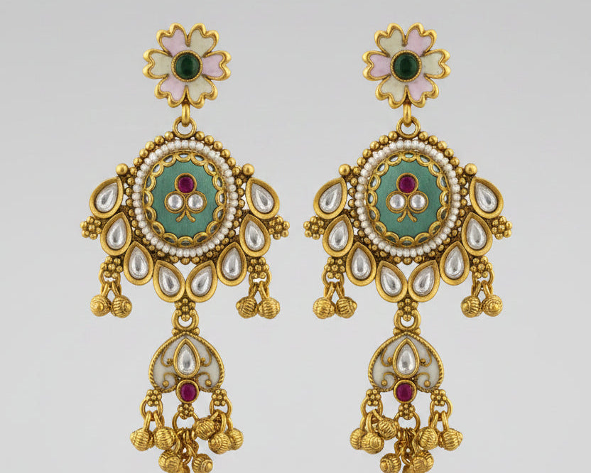 Pair of gold earrings with green and red accents on a light gray background